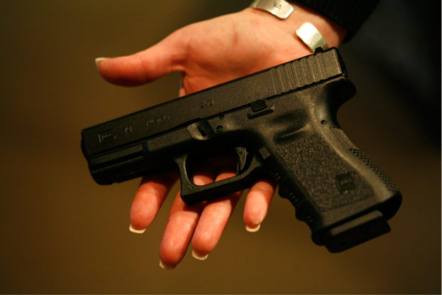 A woman holds a Glock 19, a 9 mm semi-automatic handgun.